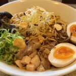 チャーシューやネギ、味付け玉子などの具材が盛り付けられた油そばの料理写真です。