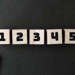 黒い背景の上に、1から5までの数字が書かれた木製のブロックが並べられている様子です。