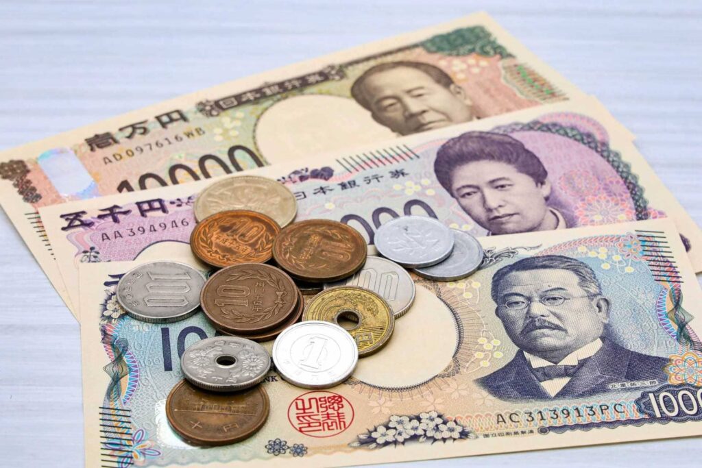 白い木目調のテーブルの上に扇状に並べられた日本の新紙幣と複数の硬貨