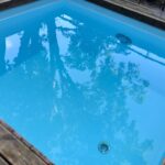 木製のデッキに囲まれた浴槽に青く澄んだ水が張られている屋外の水風呂です。
