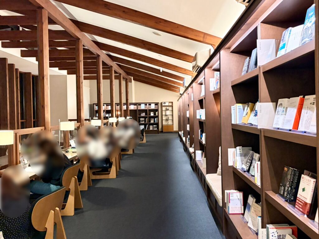 カーブドッチ ヴィネスパの館内で壁一面に本が並ぶ本棚と閲覧用の椅子が配置されています。