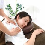 施術台の上でうつ伏せになり肩周りのボディケア施術を受けている女性