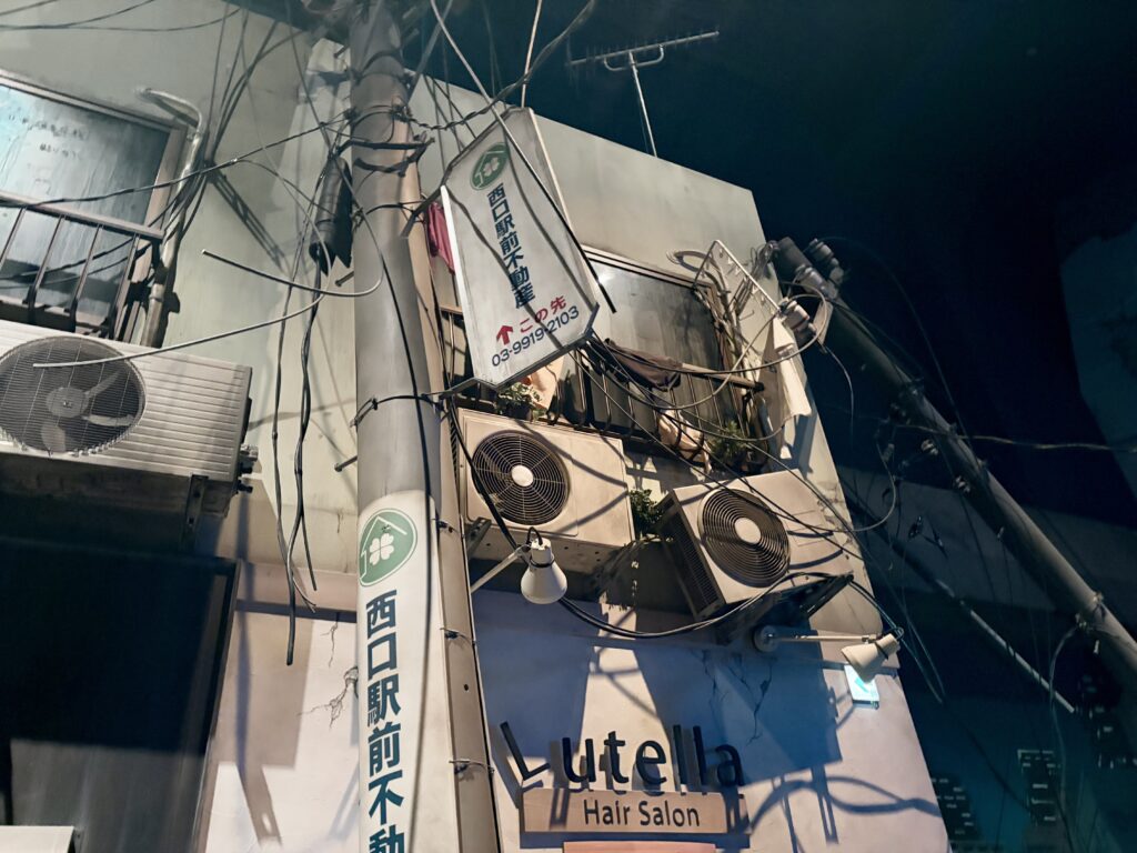 防災体験施設で再現された被災後の街並みで、傾いた電柱と垂れ下がった電線、ひび割れた建物の外壁が写っている。