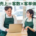 緑のエプロンを着けた男女のスタッフがノートパソコンを見ながら話しており、上部に「売上＝客数×客単価」の文字が入っています
